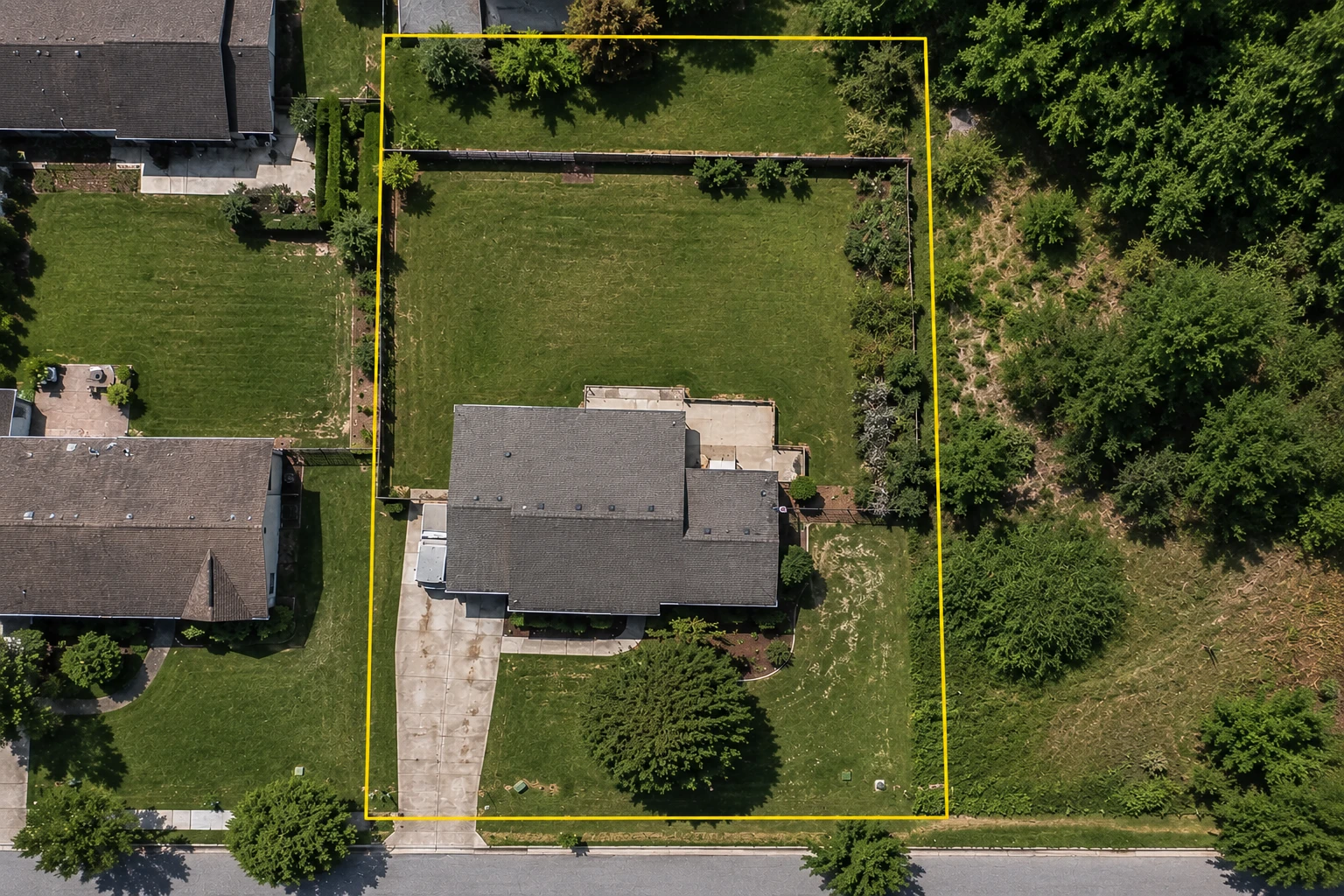 Aerial property showing a yellow parcel boundary extending beyond a backyard fence and the visible maintained yard.