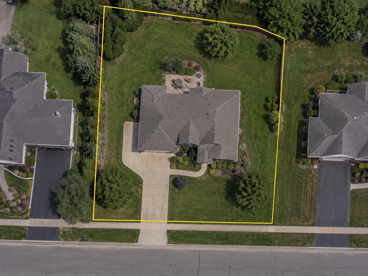 An aerial view of a residential property with its recorded parcel boundary drawn in yellow and the lawn traced separately inside it and measured at 8,460 square feet. The traced outline follows the grass around the house, driveway, patio and planting beds and leaves them out.